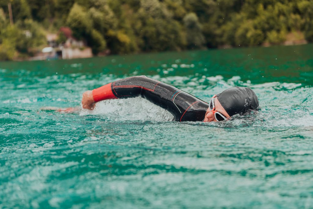 A triathlete in a professional swimming suit trains on the river while preparing for Olympic swimming